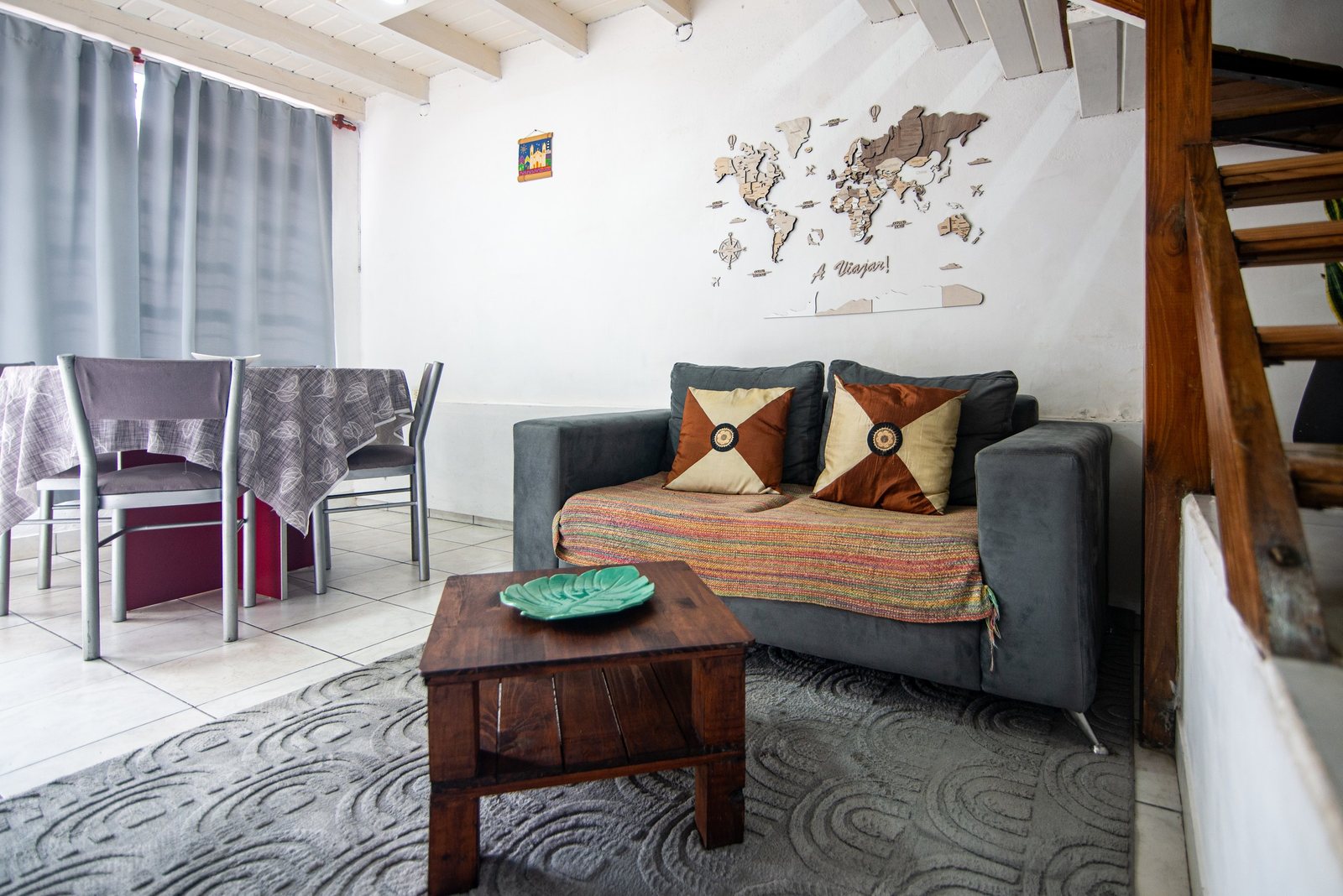 Living con sillón gris, mesa ratona de madera y mapa "a viajar!" (foto principal) – Tempo A, Posadas