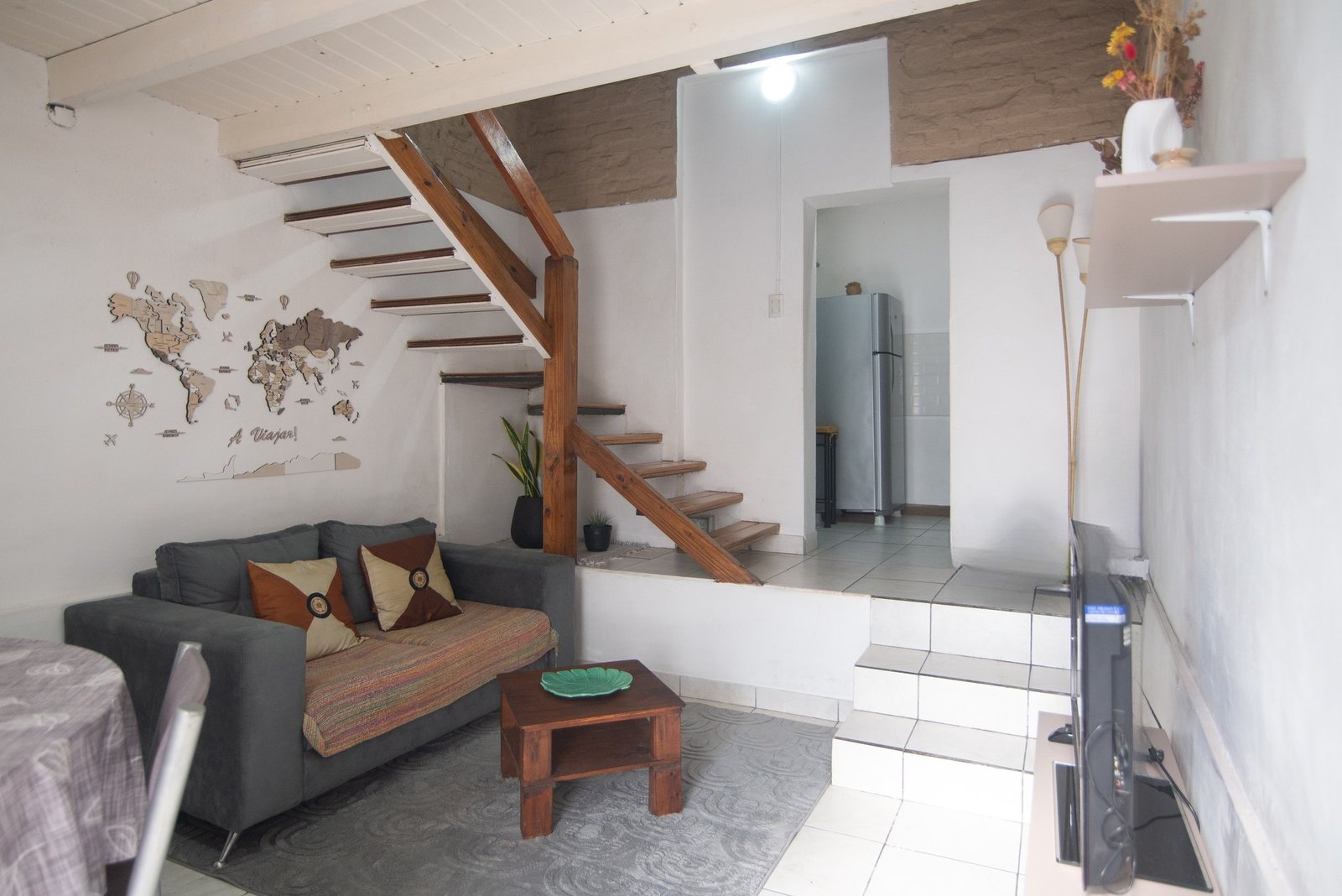 Dúplex: living, escalera de madera y cocina al fondo – Tempo A, Posadas
