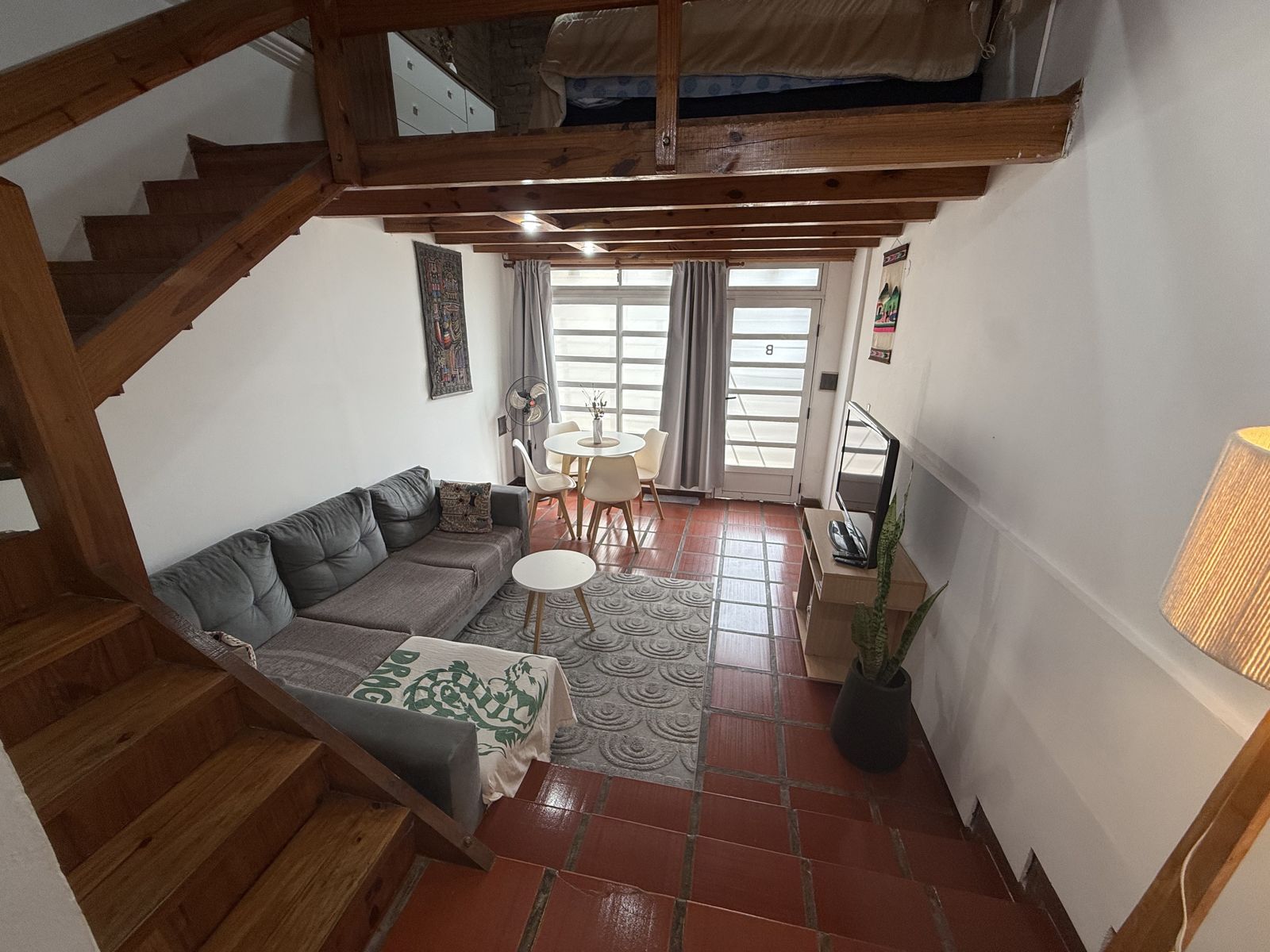 Living con escalera de madera y piso cerámico rojo – Tempo B, Posadas