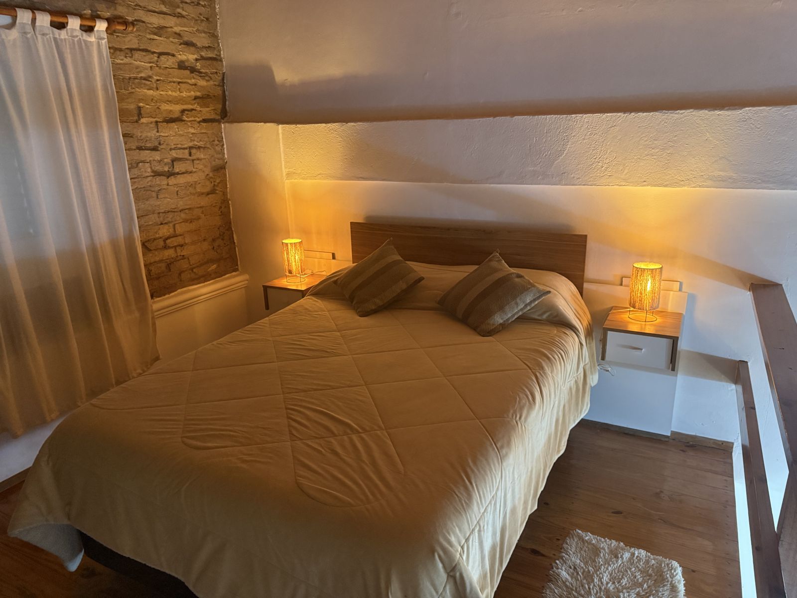 Dormitorio con luz cálida y pared de ladrillo – Tempo B, Posadas