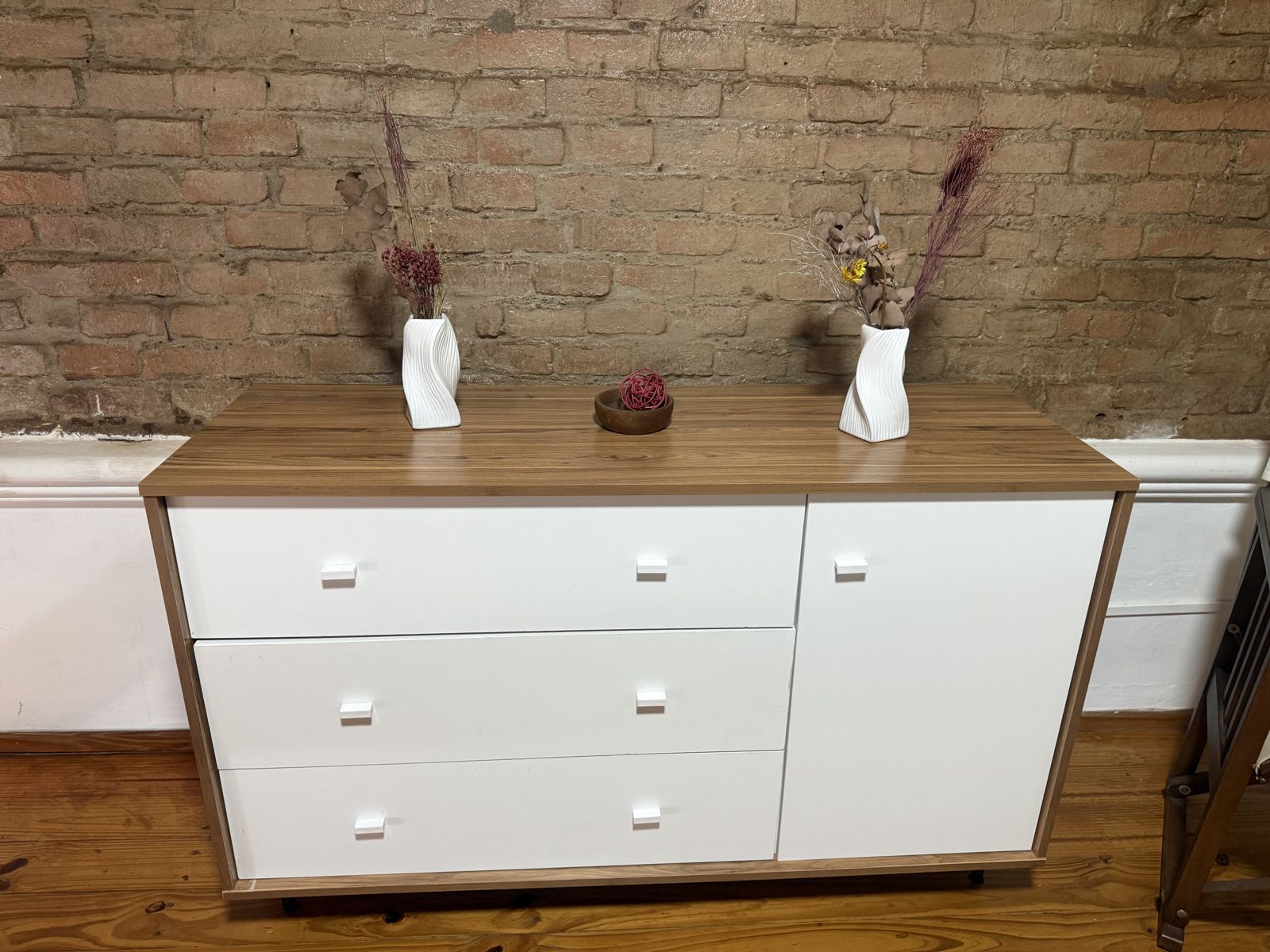 Cómoda blanca con flores secas y pared de ladrillo – Tempo B, Posadas